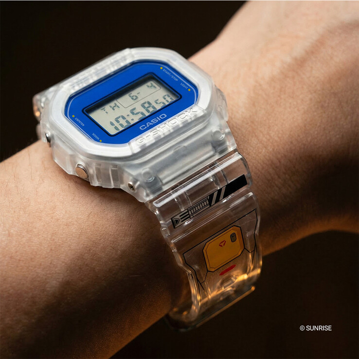 Casio G-Shock x Mobile Suit Gundam DW-5600GM26-7DR para llevar en la muñeca, con caja y correa de resina transparente, borde del bisel azul y gráficos inspirados en Gundam en la correa.