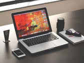 MacBook Pro sobre un escritorio oscuro junto a un teléfono inteligente, unas gafas y un cuaderno