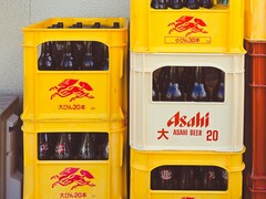 Cajas apiladas de plástico amarillo y blanco llenas de botellas de cerveza Asahi, con texto en japonés y logotipos en rojo. (Fuente de la imagen: Foto de Alazne Lazcano vía Pexels)