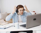 Hombre con auriculares levantando las manos con frustración frente a un portátil