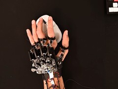 Un dispositivo exoesqueleto DIY atado a una mano mientras se utiliza un ratón de juego (Fuente de la imagen: Basically Homeless/YouTube)