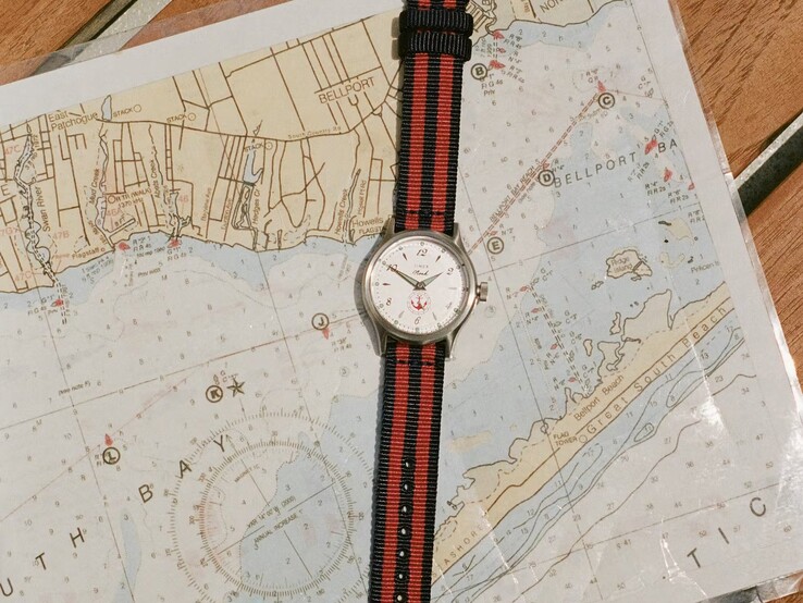 Reloj Noah x Timex MK1 Anchor con una correa de tela a rayas azul marino y rojas sobre una carta náutica.