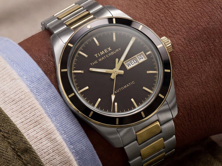 Reloj Timex Waterbury Heritage Automatic bicolor con esfera negra, lucido en la muñeca, en el que se aprecia su indicador de día y fecha y sus detalles en tono dorado.