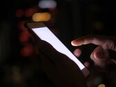 Mano que sostiene un smartphone con la pantalla iluminada en la oscuridad
