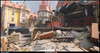Esta escena de Overwatch 2 muestra un rincón urbano devastado por la guerra, donde la mampostería derrumbada y las fachadas destrozadas atraviesan la arquitectura, por lo demás limpia y estilizada, del mapa.