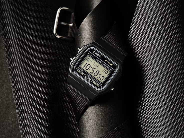 Reloj digital Casio F-91WF-1A con caja negra, correa de tejido negro y detalles plateados, fotografiado sobre un fondo oscuro con textura.