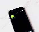 Un smartphone sobre una mesa blanca en el que se ve la aplicación de WhatsApp