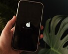 Una mano sostiene un iPhone; en la pantalla se ven iluminados el logotipo de Apple y una barra de progreso.