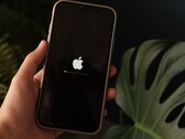 Una mano sostiene un iPhone; en la pantalla se ven iluminados el logotipo de Apple y una barra de progreso.