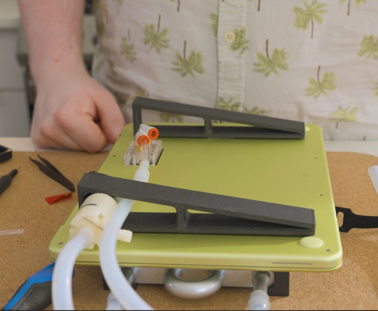 MacBook Neo modificado con bomba externa y configuración de tubos para refrigeración líquida DIY