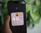 Una mano sostiene un smartphone en el que se ve una carpeta llamada «IA» con aplicaciones como Gemini, ChatGPT y Claude.