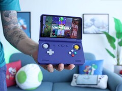 Russ, de Retro Game Corps, sostiene la videoconsola portátil Retroid Pocket Flip 2 en color morado, con la pantalla mostrando una interfaz de emulador de Sega Genesis. (Fuente de la imagen: Retro Game Corps en YouTube)