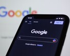 Smartphone que muestra la página de búsqueda de Google frente a una pantalla con el logotipo de Google