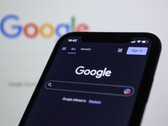 Smartphone que muestra la página de búsqueda de Google frente a una pantalla con el logotipo de Google