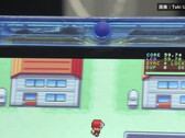 Primer plano de la consola portátil FPGBA SP azul transparente ejecutando Pokémon, con un contador de 59.74 FPS visible.