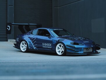 Coche de drift azul con motivos de G-Shock y Toyo Tires aparcado frente a un edificio industrial.