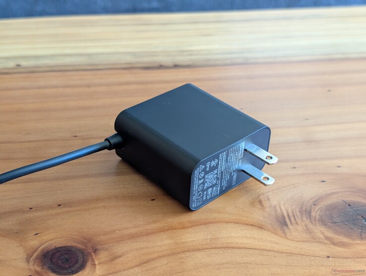 Adaptador de CA USB-C de 65 W que se incluye con el Lenovo Yoga Slim 7 14. Obsérvese que las clavijas de CA no son retráctiles y que el cable USB-C está integrado en el otro extremo.