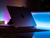 Un MacBook entreabierto en una habitación oscura, con la luz que se cuela por la rendija y se derrama sobre el escritorio
