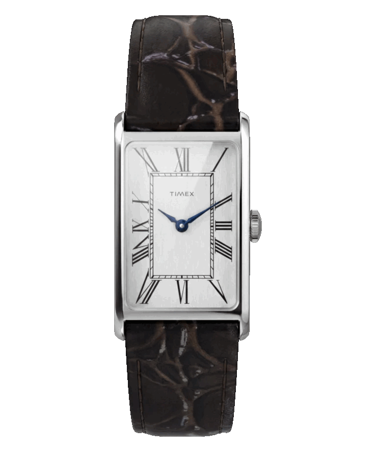 La esfera en tono plateado presenta una textura cepillada verticalmente, números romanos alargados, agujas de color azul metálico y un cristal mineral abombado.