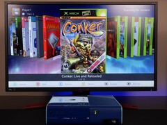  Una Xbox 360 azul modded ejecutando un dashboard homebrew personalizado en un monitor, mostrando el juego &quot;Conker: Live and Reloaded&quot; junto a otros títulos de Xbox y emuladores. (Fuente de la imagen: Modern Vintage Gamer en YouTube)