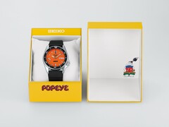 Reloj automático Seiko 5 Sports x Popeye HDB013, con esfera naranja, junto a su estuche de presentación amarillo de edición limitada.