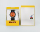 Reloj automático Seiko 5 Sports x Popeye HDB013, con esfera naranja, junto a su estuche de presentación amarillo de edición limitada.