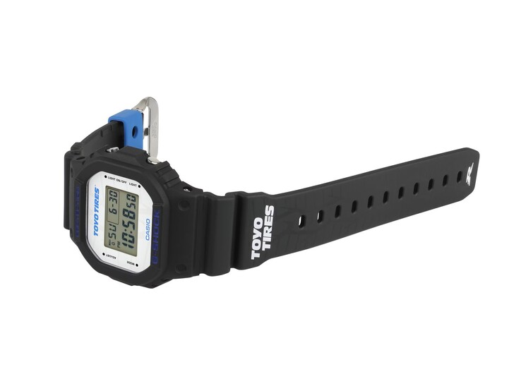 Los gráficos de la banda de rodadura de los neumáticos, la marca Toyo Tires y una trabilla de la correa azul en contraste enfatizan la inspiración automovilística del reloj.