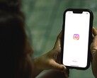 Mujer que sostiene un smartphone con ambas manos; en la pantalla se ve la pantalla de inicio de Instagram