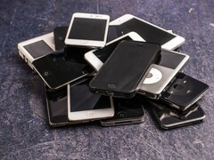 Montón de teléfonos inteligentes en desuso sobre una superficie gris