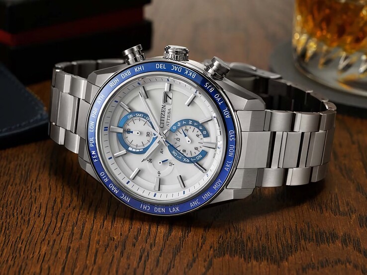 Cronógrafo Citizen Attesa AT8297-51L apoyado sobre una mesa de madera, mostrando su esfera azul marino, detalles en oro rosa y bisel negro de hora mundial.