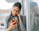Una mujer mira su smartphone con expresión seria.