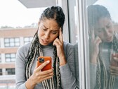 Una mujer mira su smartphone con expresión seria.