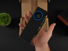 Una persona sostiene la GPU Intel Arc Pro B50 de bajo perfil para estaciones de trabajo con un refrigerador tipo soplador, mostrada contra su caja de embalaje. (Fuente de la imagen: ETA Prime vía YouTube)