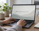 Las manos sobre el teclado de un ordenador portátil; un control deslizante en el extremo izquierdo de la pantalla
