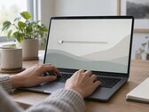 Las manos sobre el teclado de un ordenador portátil; un control deslizante en el extremo izquierdo de la pantalla