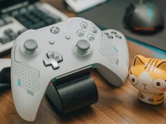 Mando de Xbox blanco descansando sobre un escritorio de madera junto a una pequeña figurita de gato (Fuente de la imagen: FOX ^.ᆽ.^= ∫ via Pexels)